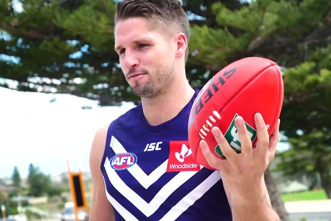 A mid shot of Fremantle recruit Jesse Hogan in a Dockers jumper with a red football in his left hand.