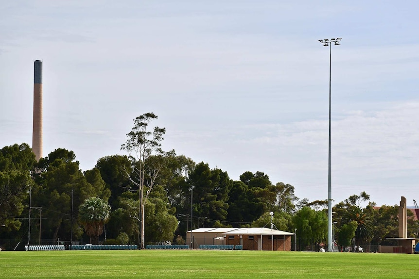 A sporting field at Port Pirie, with the lead smelter stack in the background.
