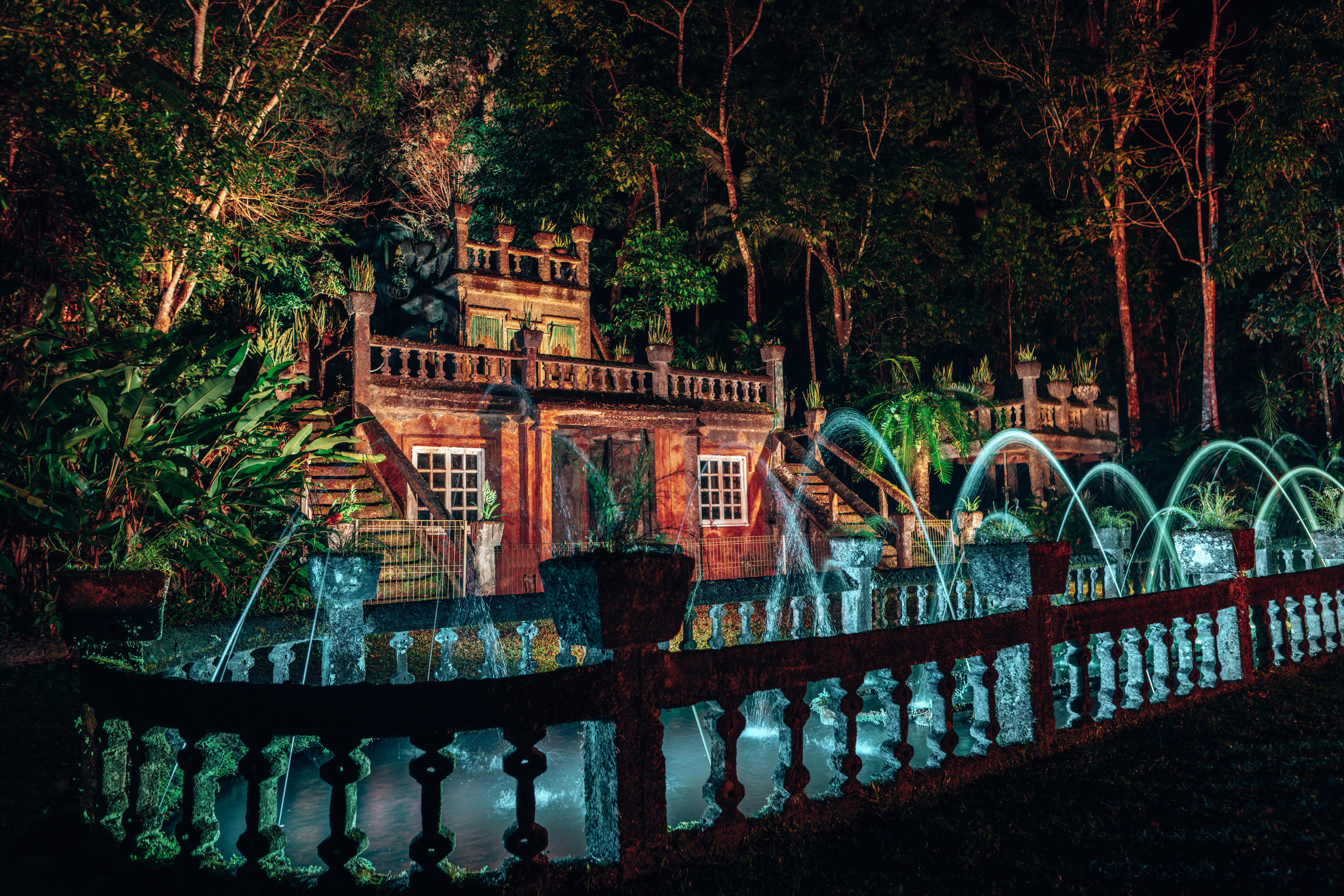 Una foto del castillo con una fuente de agua activa, iluminada por focos por la noche.