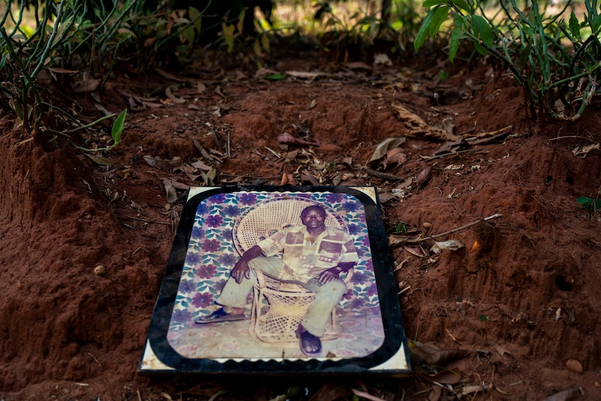 A photograph of an African man lays on top of his grave.
