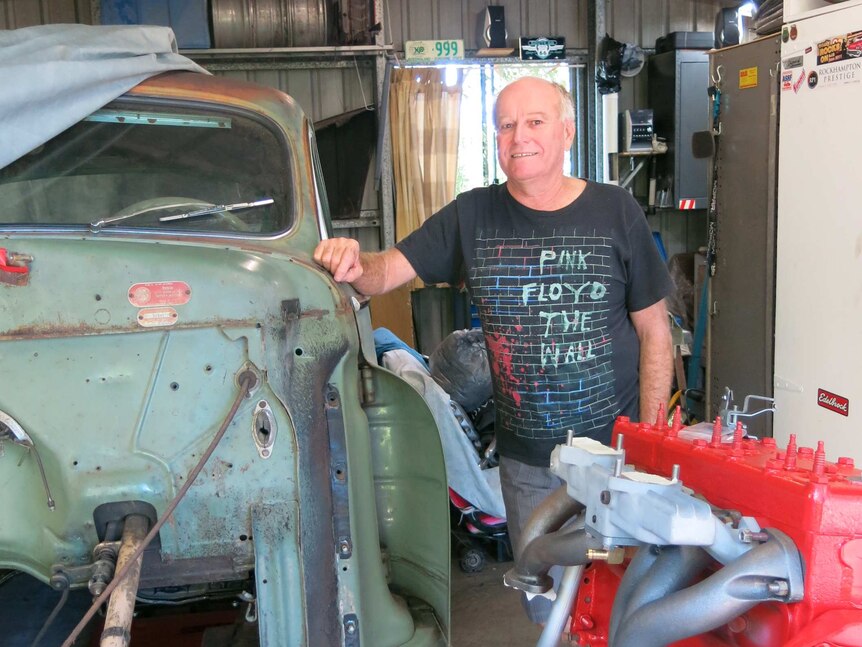 Motor enthusiast Glen Hamilton stands in a shed next to a 1948 Dodge Business Coup