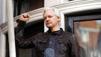Julian Assange holds up his fist
