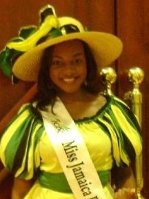 A black woman dressed in Jamaican colours wearing a sash with Miss Jamaica written on it