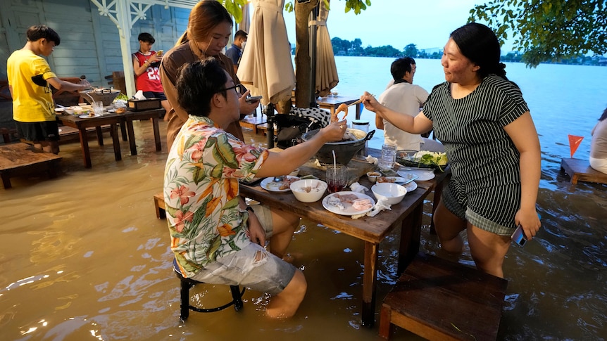 Customers of the riverside Chaopraya Antique Café enjoy themselves in knee high depth water