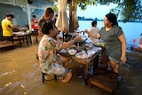 Customers of the riverside Chaopraya Antique Café enjoy themselves in knee high depth water