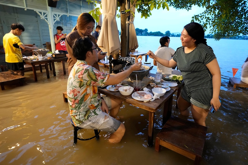 Customers of the riverside Chaopraya Antique Café enjoy themselves in knee high depth water