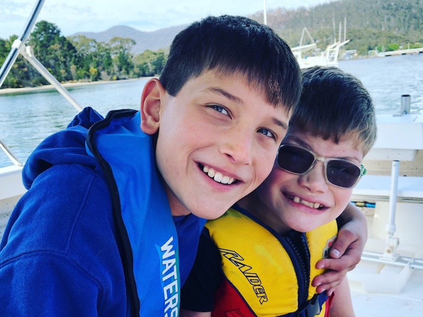 Two boys on a boat smile at the camera