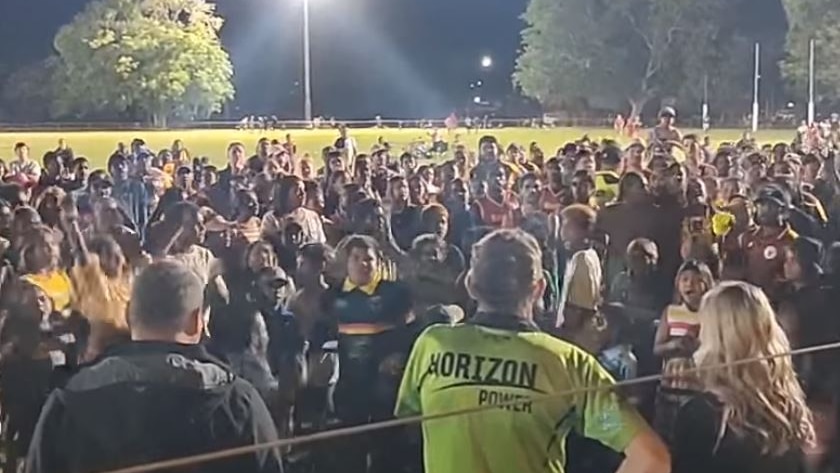 A crowd gathers in front of a man in a bright lime green shirt