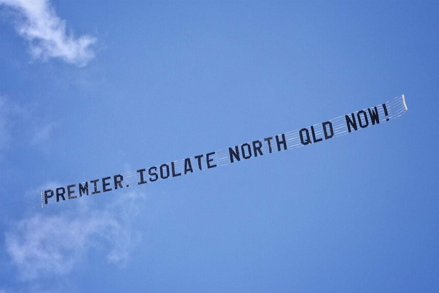 Banner in sky trailing behind plane - Premier. Isolate North Qld Now! flying over Brisbane