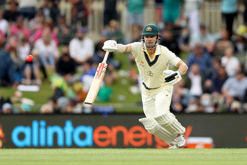 Australian hitter Travis Head leaves a hand on his bat as he completes a shot in an Ashes Test.