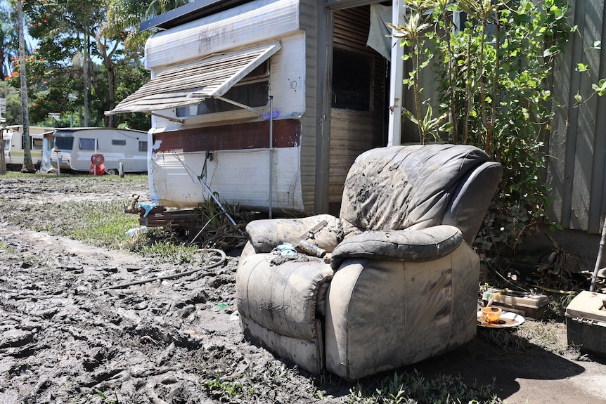 A chair outside a caravan on the edge of a mud puddle
