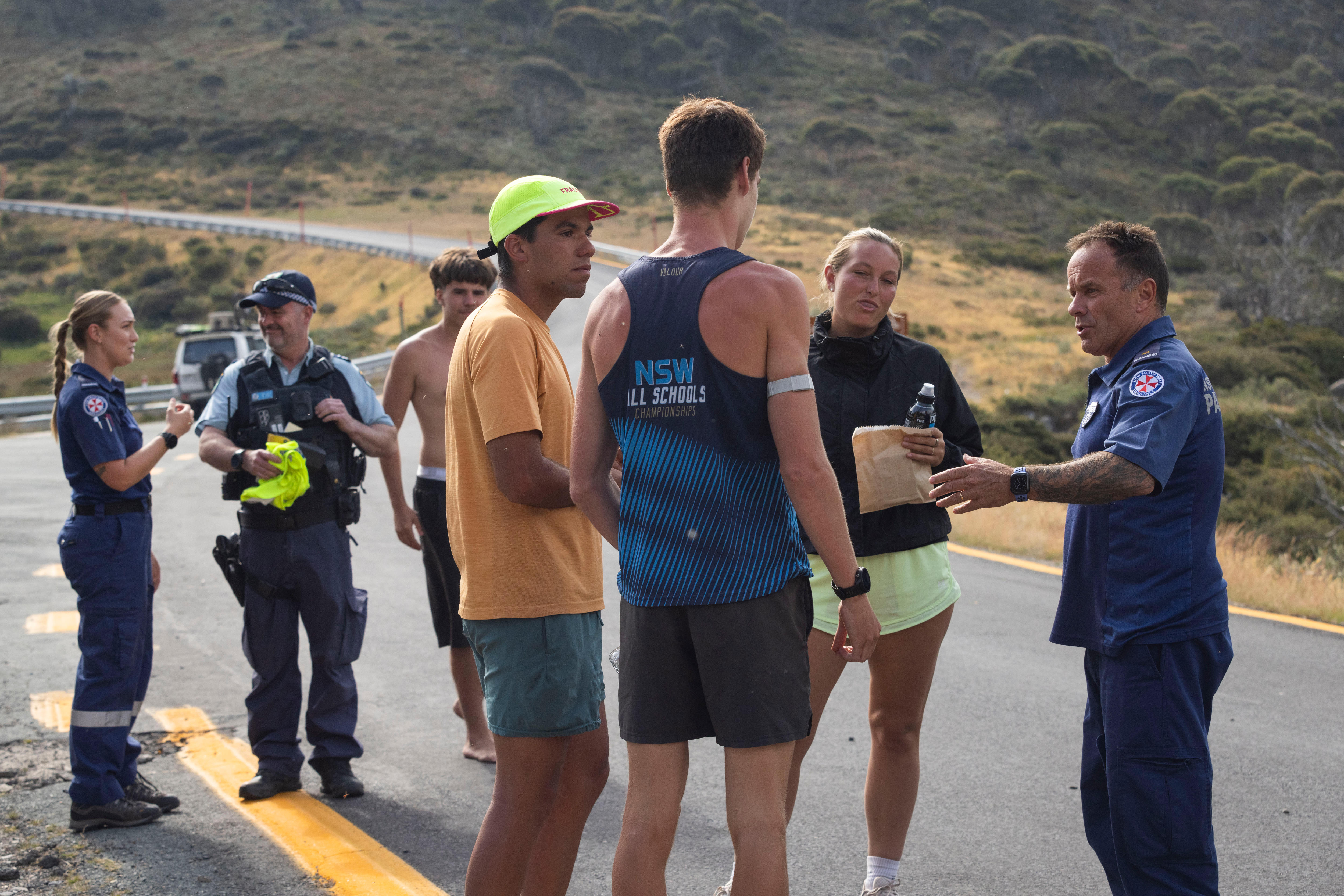 Um grupo de pessoas conversando com funcionários do serviço de emergência em uma estrada. 