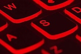 A computer keyboard lit up in red.