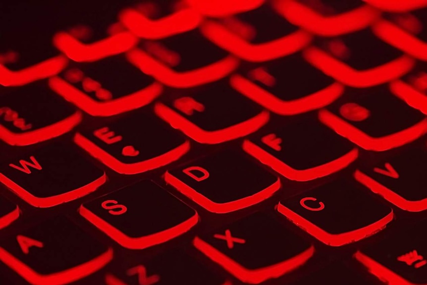 A computer keyboard lit up in red.