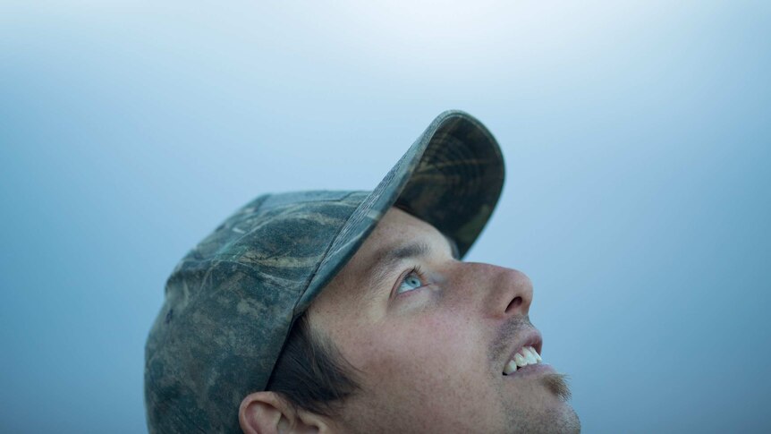 Wearing a camouflage cap, duck hunter Dean Rundell eyes the sky.