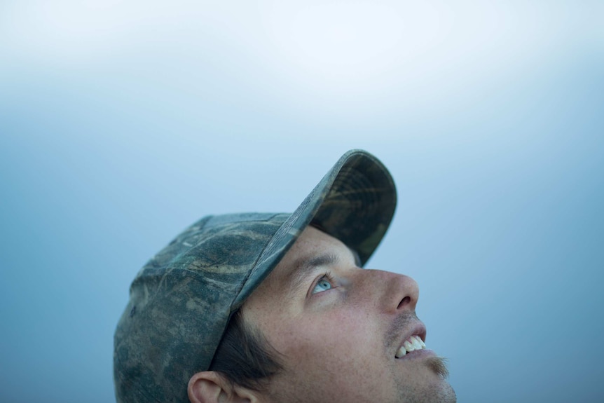 Wearing a camouflage cap, duck hunter Dean Rundell eyes the sky.