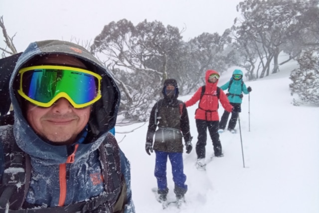 A man in the snow with three people behind him