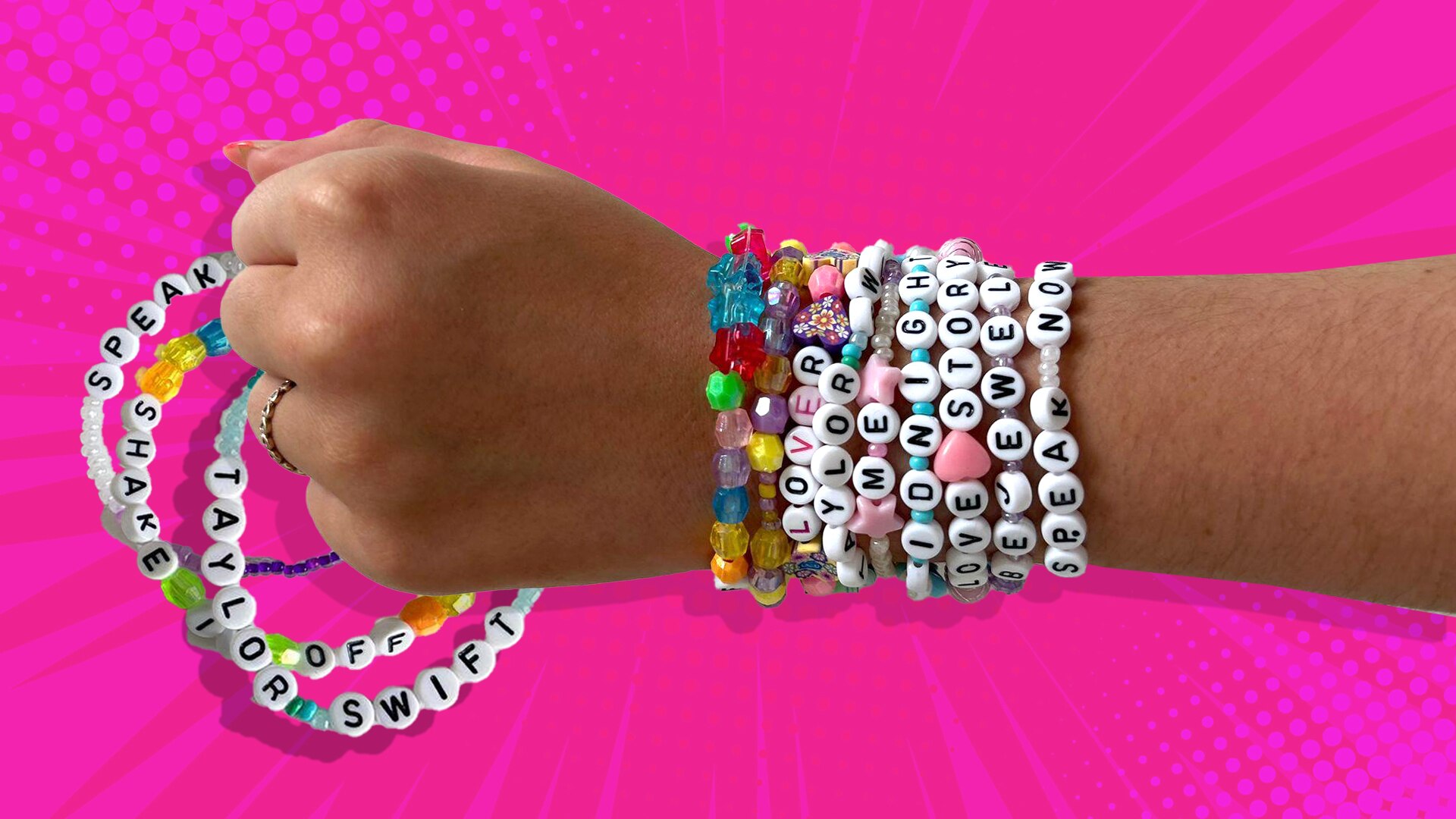 A close up on the hand and wrist of a young girl, wearing bright bracelets with letter bead spelling Taylor Swift album names.
