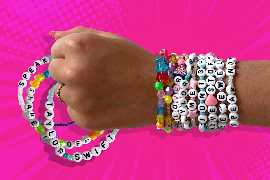 A close up on the hand and wrist of a young girl, wearing bright bracelets with letter bead spelling Taylor Swift album names.