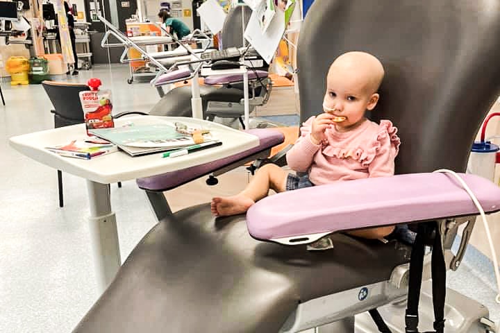 a young girls sits in a hospital ward eating lunch