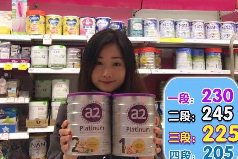 An Asian-looking woman holding cans of baby formula in front of an Australian supermarket shelf with Chinese writing overlaid