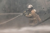 A firefighter is shrouded in smoke while fighting a fire