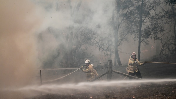 A firefighter is shrouded in smoke while fighting a fire