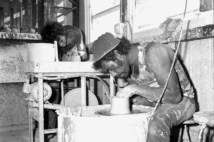 A black and white photo of two Indigenous men working at pottery wheels.