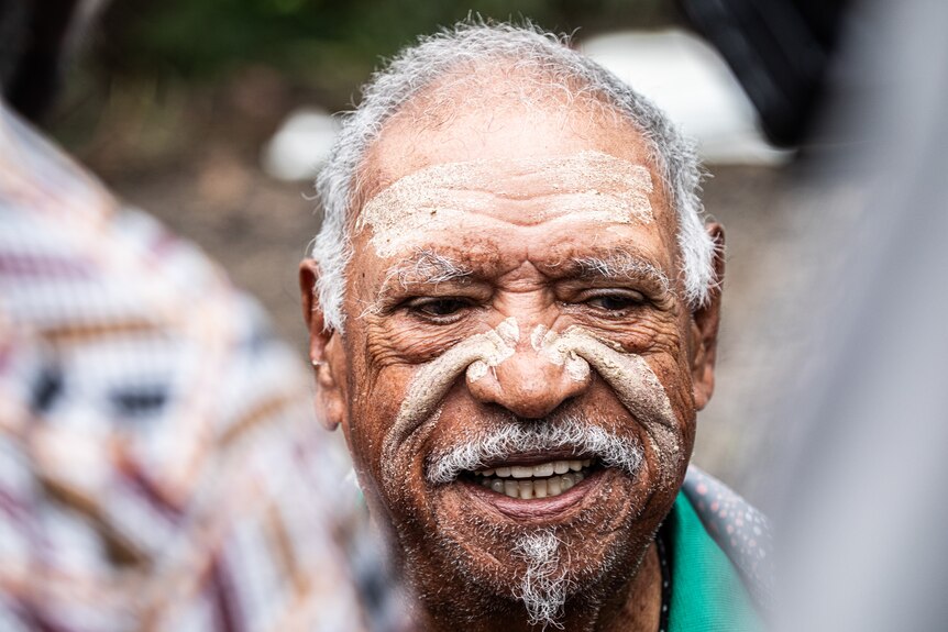 Aborignal Elder portrait of Herbert Marshall smiling wearing cultural paint on his face in Newry State Forest
