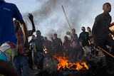 Protestors in Burundi run across a fire towards police