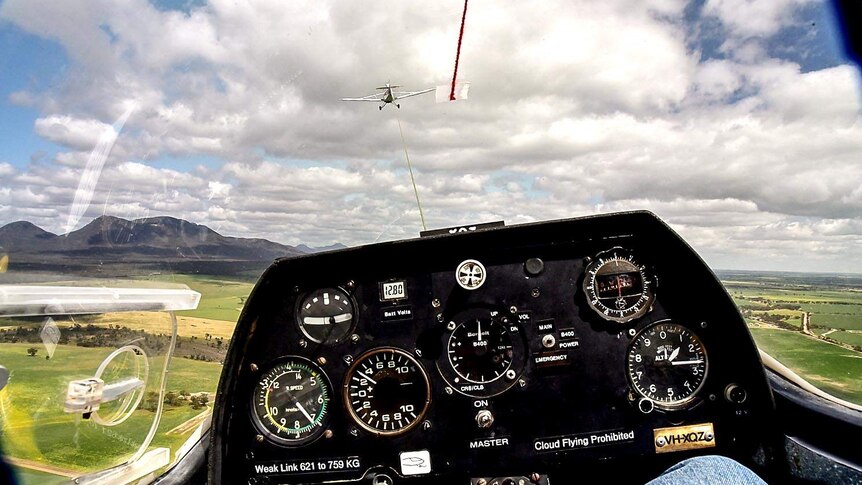 View from the cockpit of a glider as it is towed behind a plane.