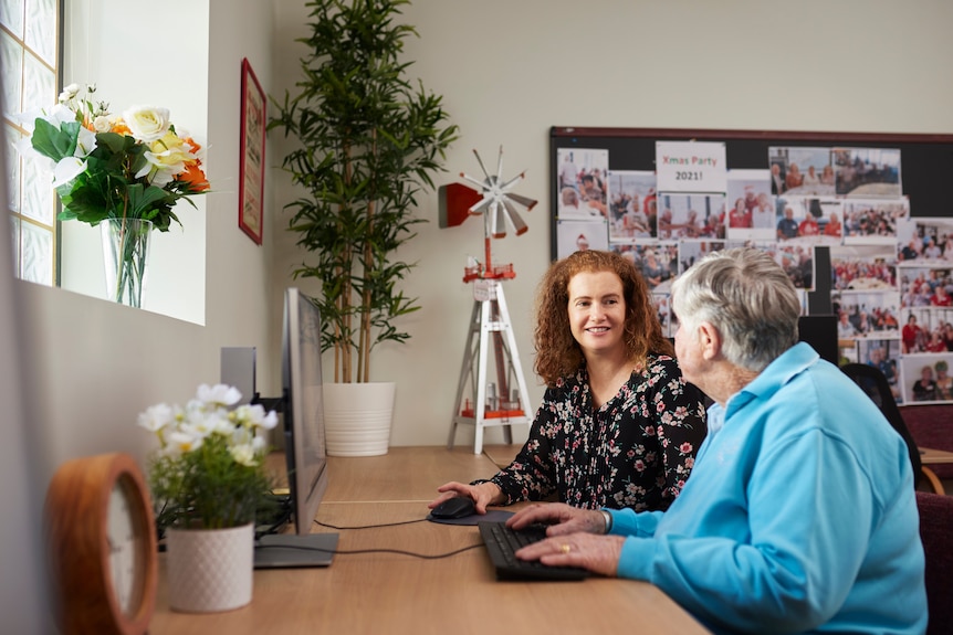 Counselor and woman sit at desk with vases of fresh flowers
