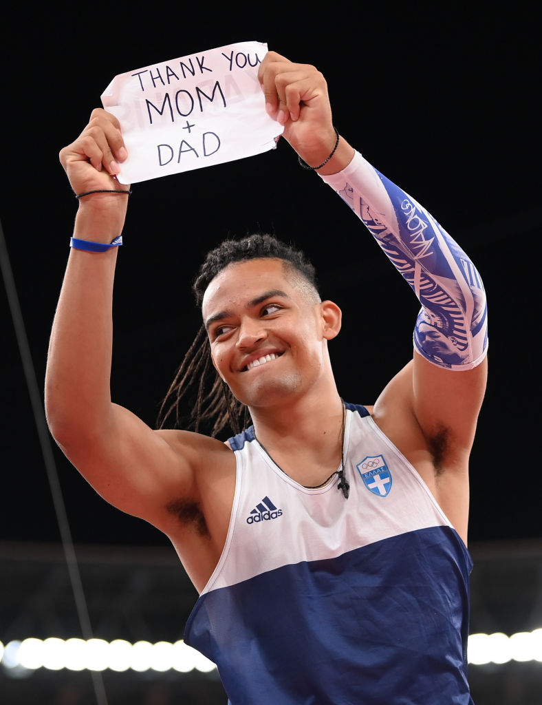 Emmanouil Karalis smiles as he holds up a sign that says 'thank you mum and dad'.