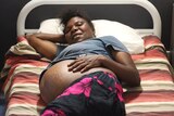 a pregnant woman lying on a bed