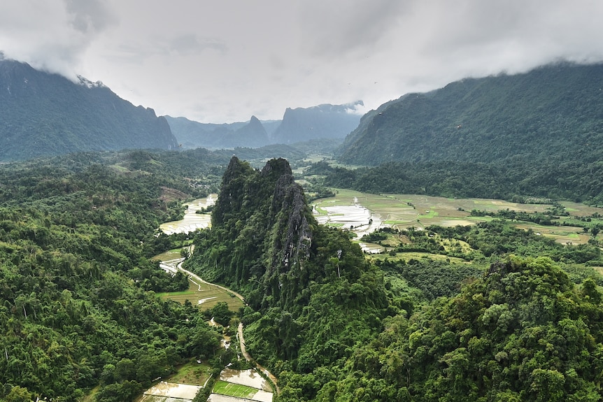 A limestone outcrop sits in a lush ravine next to river.