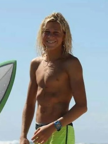 Cooper Allen in board shorts at beach with surfboard