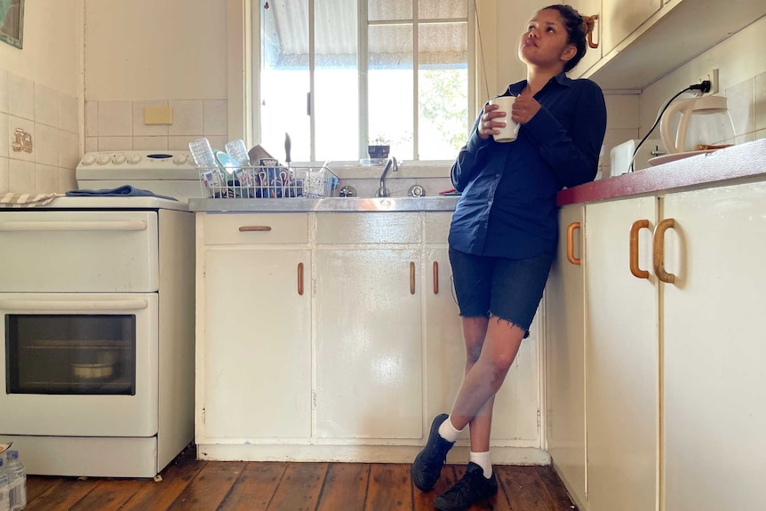 Kimberly leans against the kitchen cupboard in her modest home.