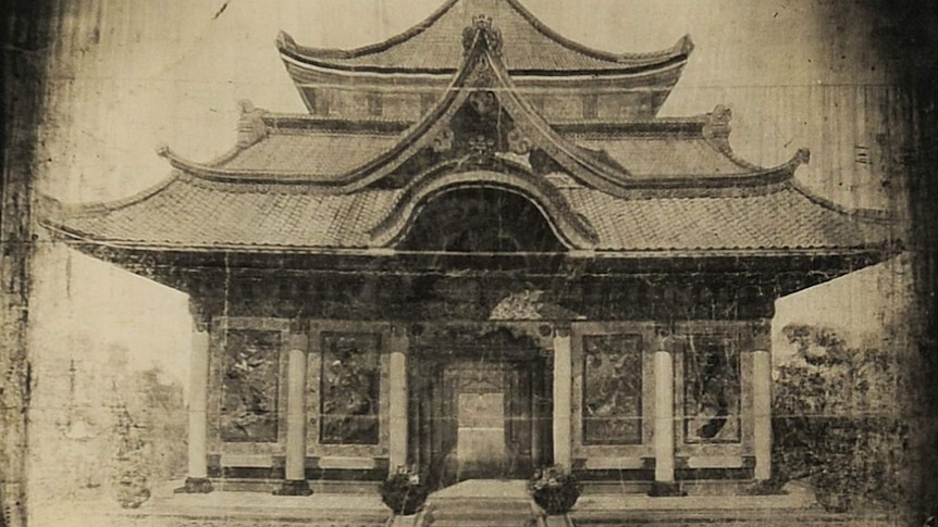 A black and white photograph of a painted backdrop depicting a Japanese temple.