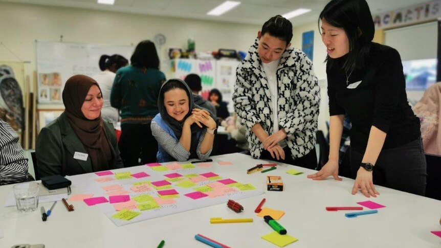 Four women look at brightly coloured post it notes at a workshop