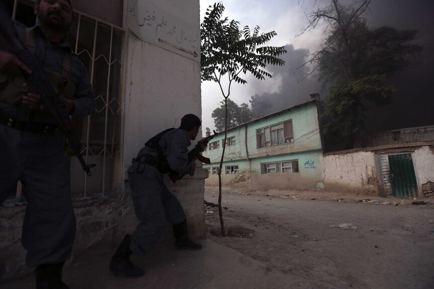 Afghan policemen take up position as smoke billows from the site of an explosion in Kabul