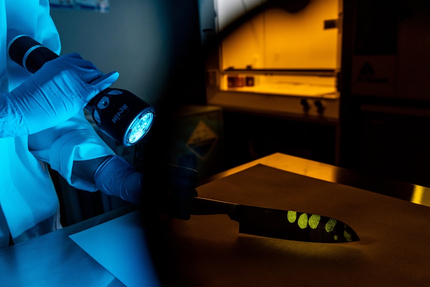 A knife with fingerprints under a fluorescent light.