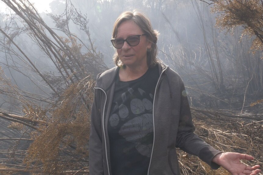 a woman stands in amongst burnt peat swamp