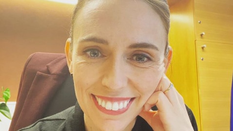 Smiling brunette woman in black coat in office