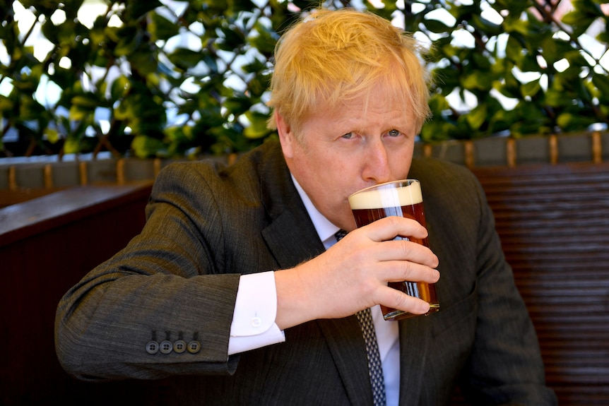 Boris Johnson sirote une pinte dans le café en plein air.