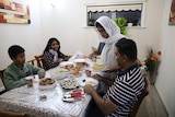 A family sitting at their kitchen table waiting to eat a meal. 