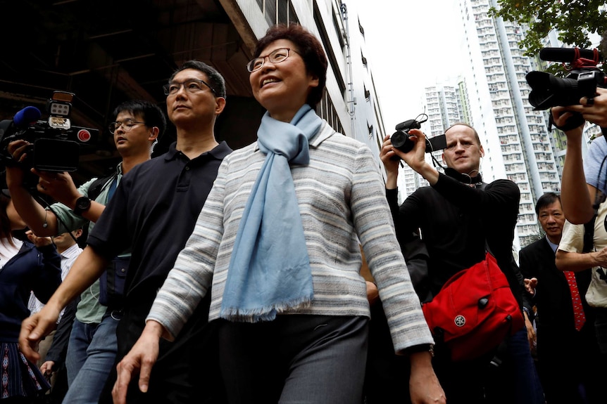 Carrie Lam walks on a streets with a crowd around her