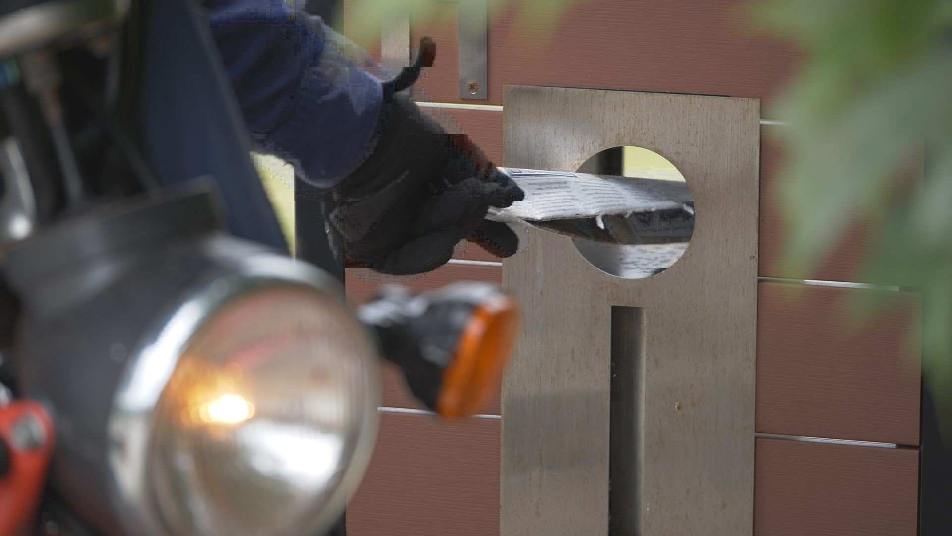 A postman puts a newspaper into a letterbox.