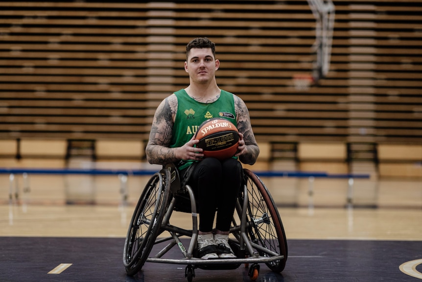 A man in a wheelchair on a basketball court holding a basketball