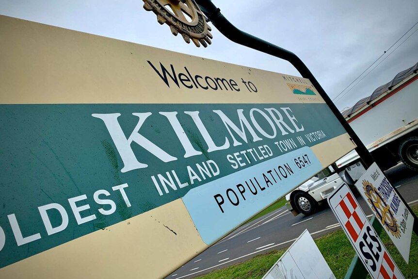 A faded yellow and green sign welcoming drivers to Kilmore