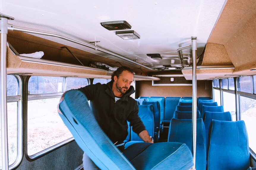 Kevin Craft holds a seat from a bus, which he converted into a mobile home for his family.